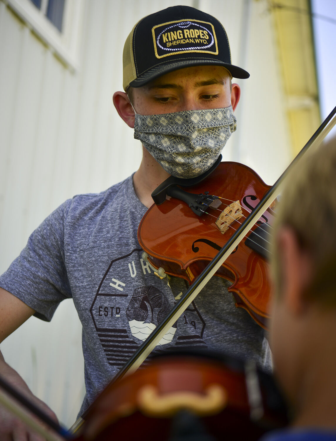 Tyler McWhorter helps a younger student learn a new technique on the fiddle